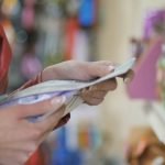 A woman is holding a bag of pet food and looking at the ingredients on the back in a pet store