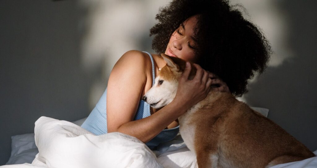 A woman is hugging a dog in bed