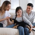 A family is sitting with their dog on a couch