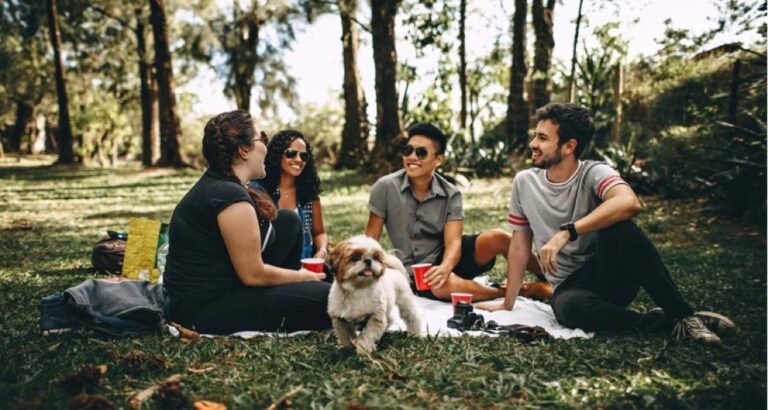 Friends sitting outside in the grass with a dog