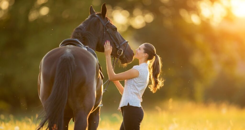 A woman is petting a horse on their head outside