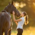 A woman is petting a horse on their head outside
