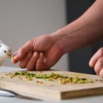 A white bird is being fed vegetables by a person's hand