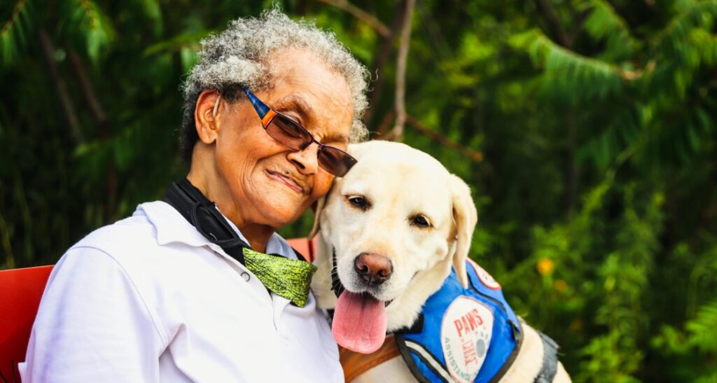 A woman sitting with a therapy dog outside