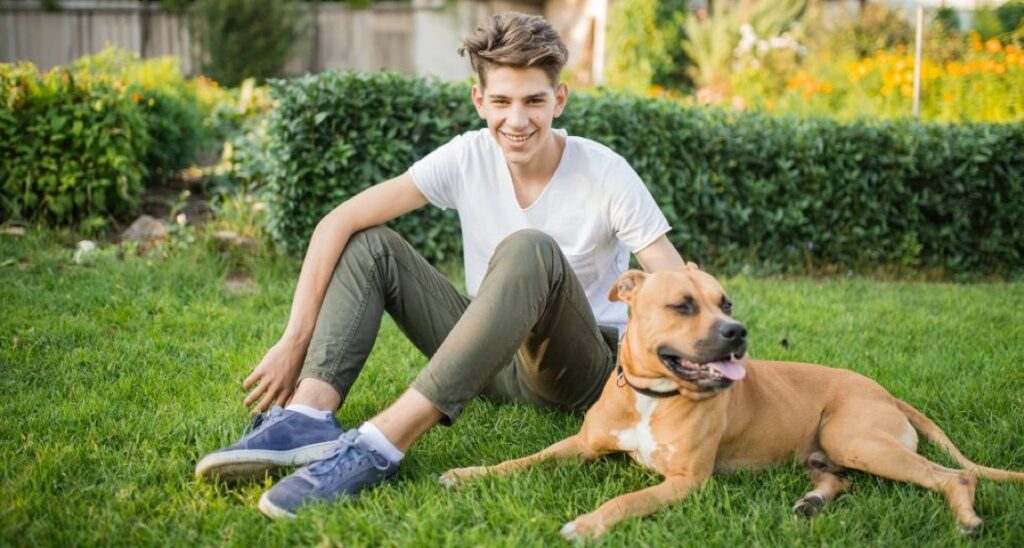 A boy is sitting with a boerboel in the grass