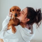 A woman is kissing a dog in their arms