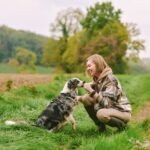 A woman with an Australian shepherd outside in the grass