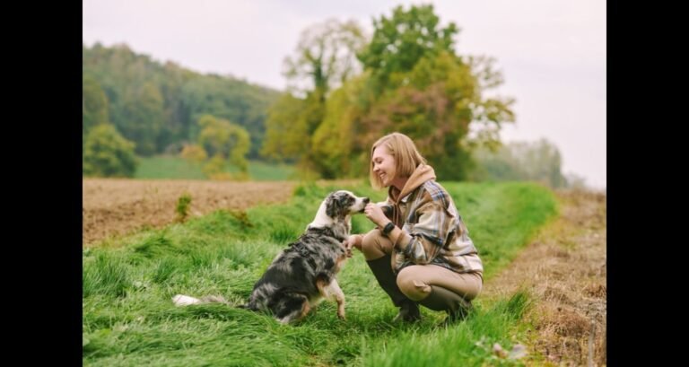 A woman with an Australian shepherd outside in the grass