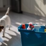 A dog is standing beside a blue container of cleaning supplies