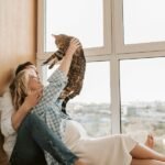 A woman is holding up a cat while sitting with a man