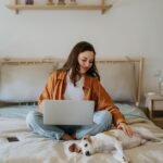 A woman is stroking a dog on a bed