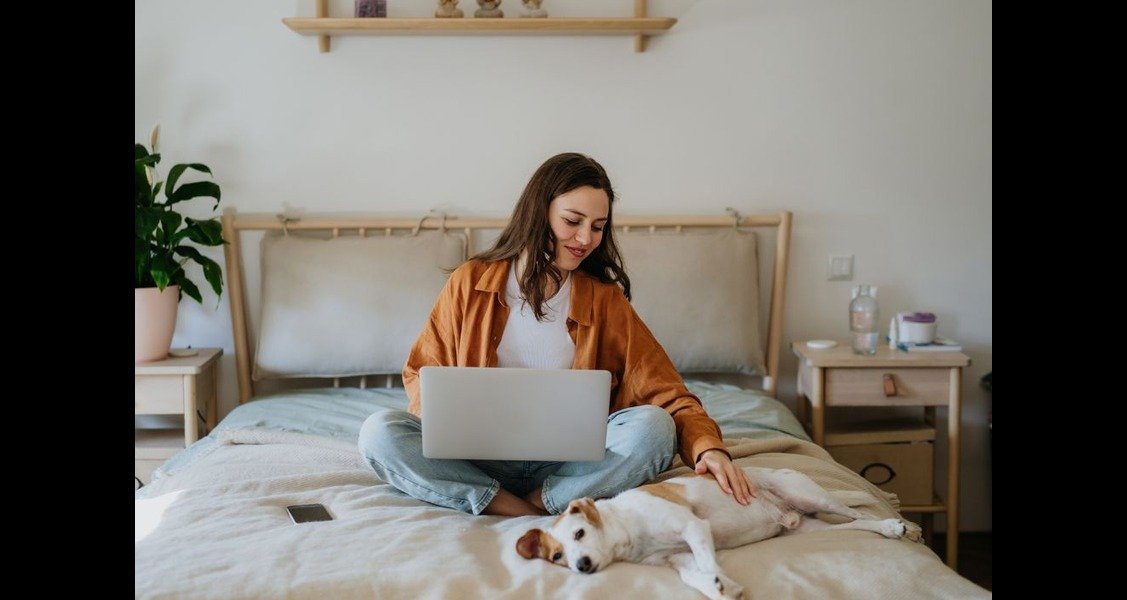 A woman is stroking a dog on a bed