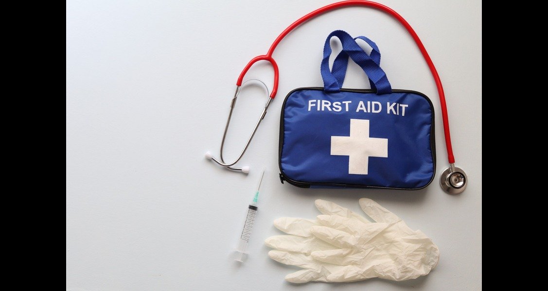 An image of a first aid kit, stethoscope, gloves and syringe