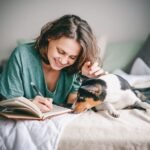 A woman is lying in bed with a dog