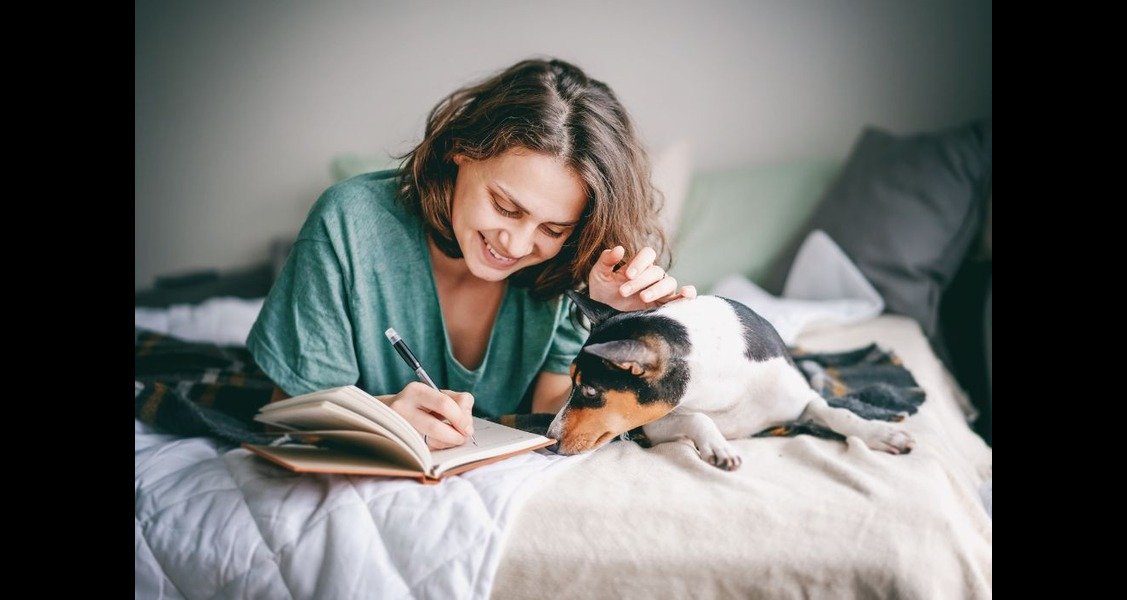 A woman is lying in bed with a dog